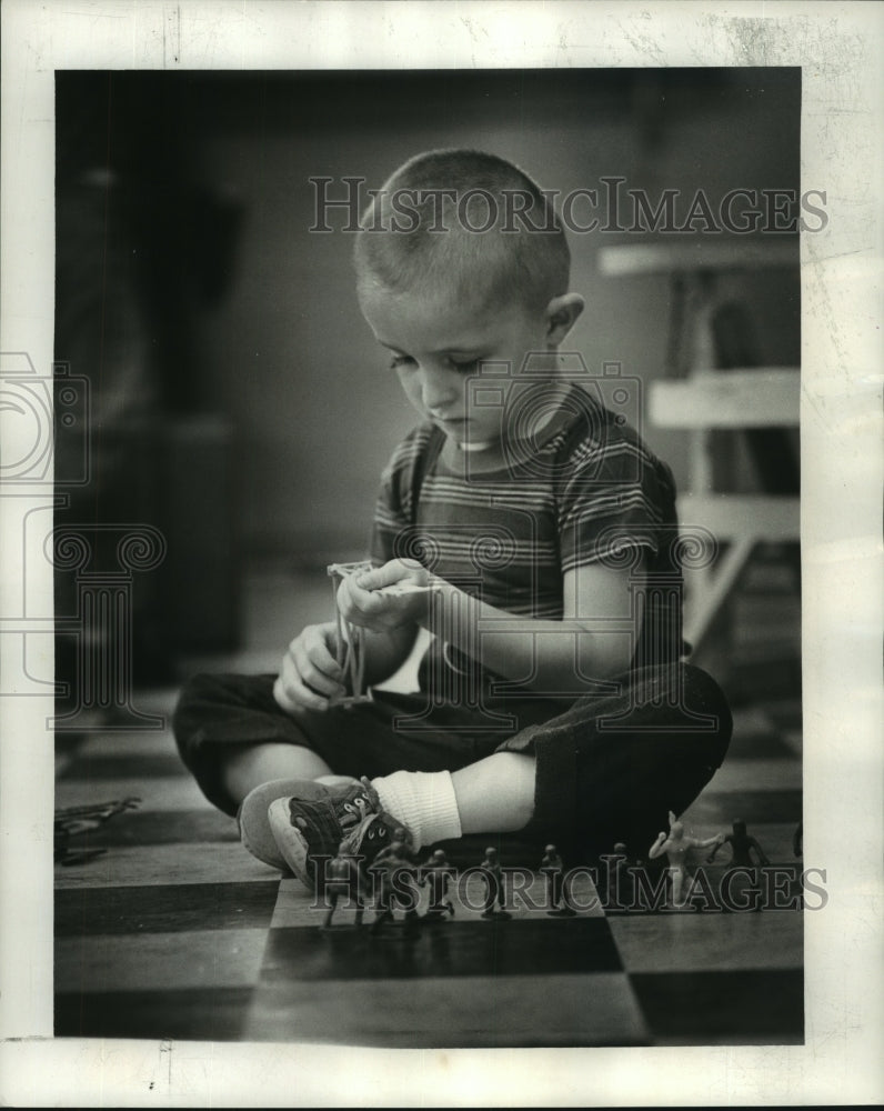 1963 Press Photo This boy puts together a fence with individual pieces. - Historic Images