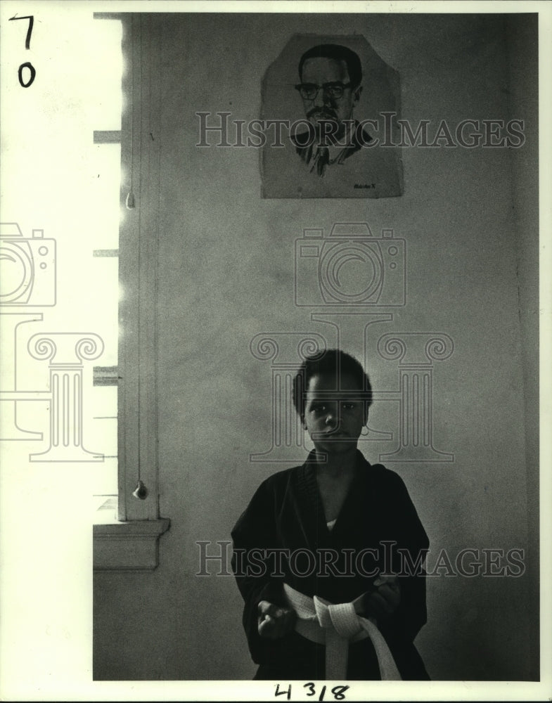 1983 Press Photo Taiji Salaam strikes martial arts pose under Malcom X poster - Historic Images