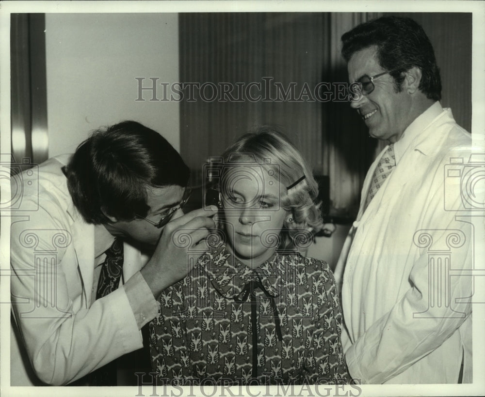 1974 Press Photo Paul B. Guevara examining the ear of Mrs. Kathy C. Brackey - Historic Images