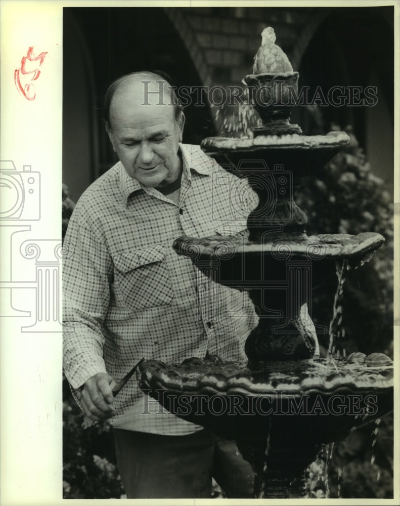 1989 Press Photo Leon Graugnard, does spring cleaning on his front yard fountain - Historic Images