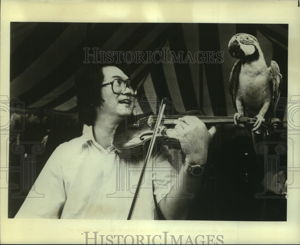 1980 Press Photo Violinist Henry Lee plays a few notes for Mr. Magoo, a macaw - Historic Images