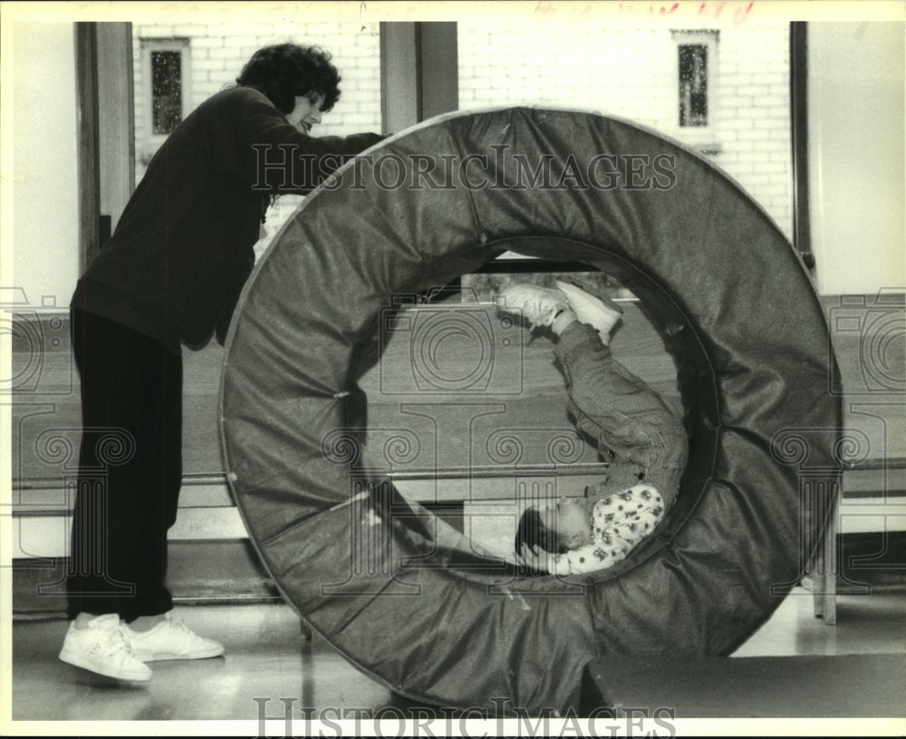 1992 Press Photo Jeane Cohen rolls her son Bryce, 2, in a foam ring- Baby Gym - Historic Images