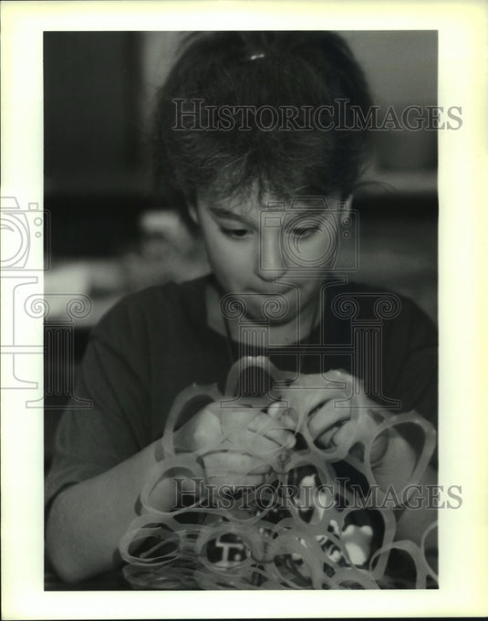 1990 Press Photo Melissa Puglia ties "six-pack" plastic together for tote bags. - Historic Images