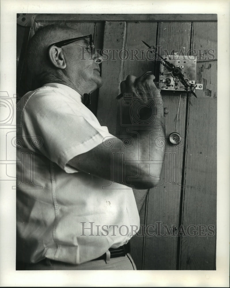 1963 Press Photo Grindle examines works of 150-year-old French clock.-Historic Images