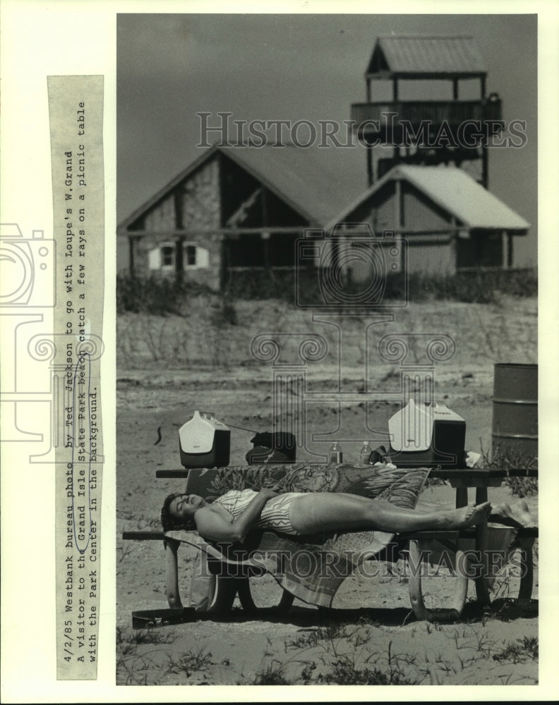 1985 Press Photo Grand Isle State Park beach visitor sunbathing on picnic table - Historic Images