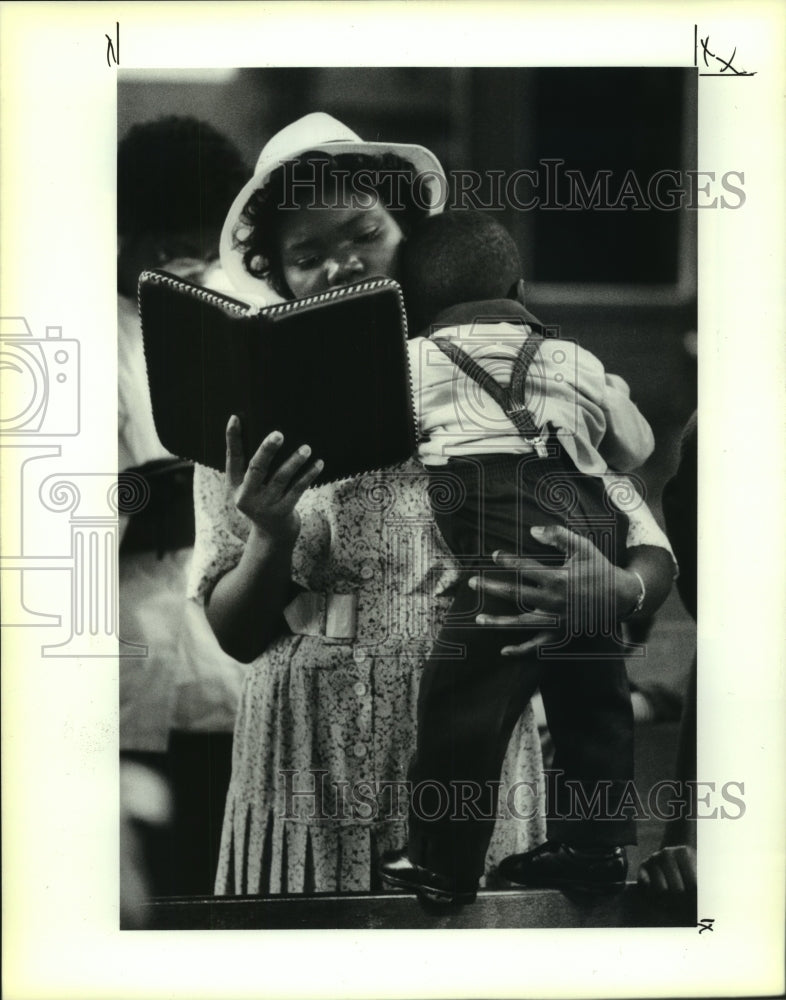 1991 Press PhotoRoseline Antoine sings as she holds her son during services. - Historic Images