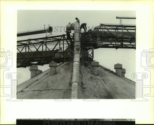 1994 Press Photo Workers prepare to connect piping atop a grain storage facility - Historic Images