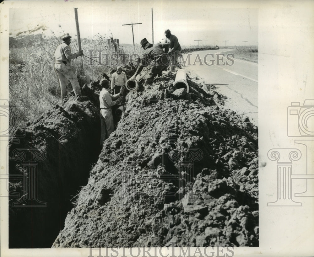 1962 Workers lower another pipe section in place, Grand Isle, LA - Historic Images