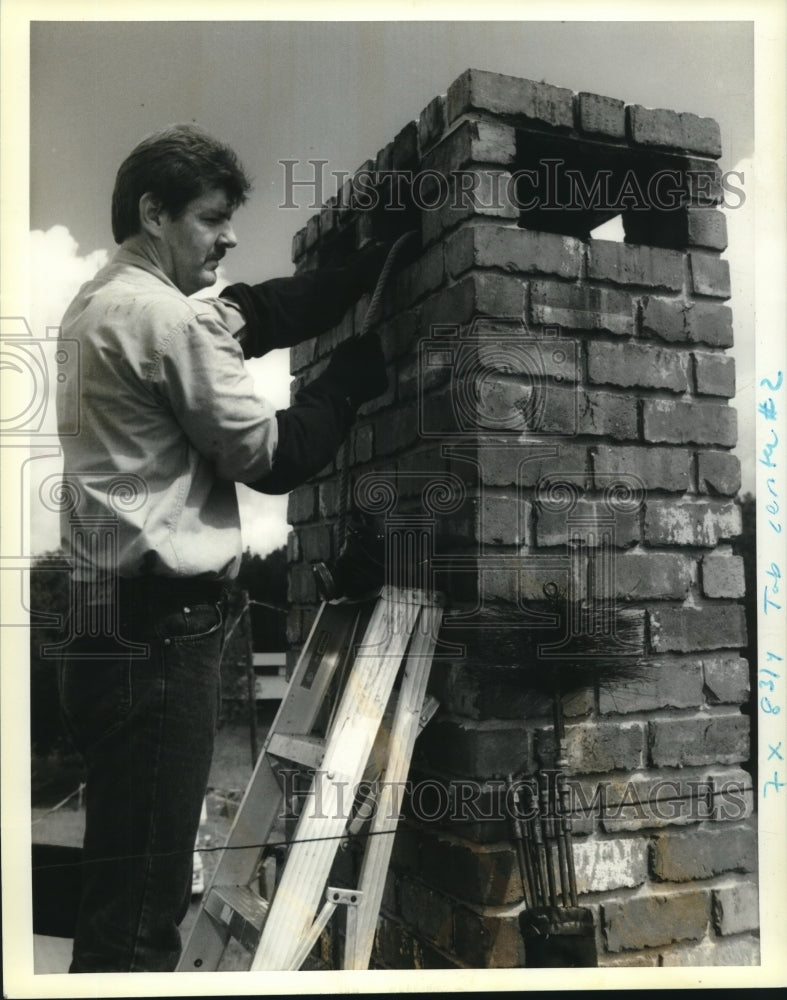 1990 Press Photo H.J. Hadley runs weighted brush down capped chimney - Historic Images