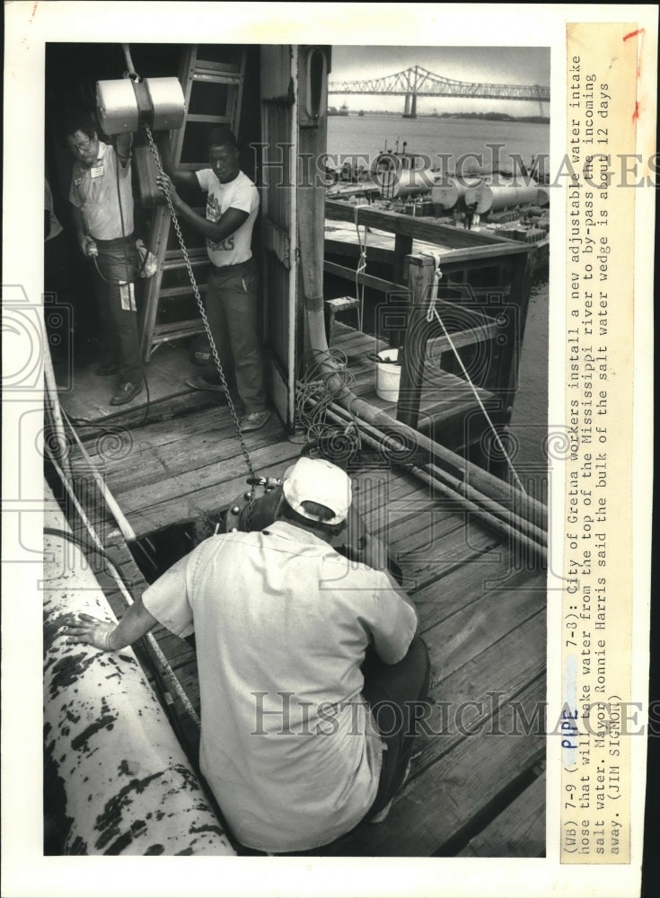 1988 Press Photo Gretna workers install a new adjustable water intake hose. - Historic Images