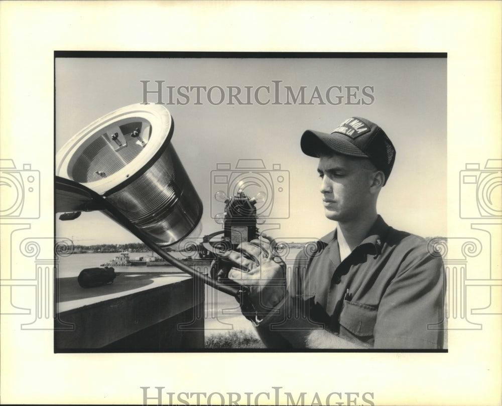 1990 Press Photo Coast Guard member Trip Rizzo inspects a navigational light - Historic Images