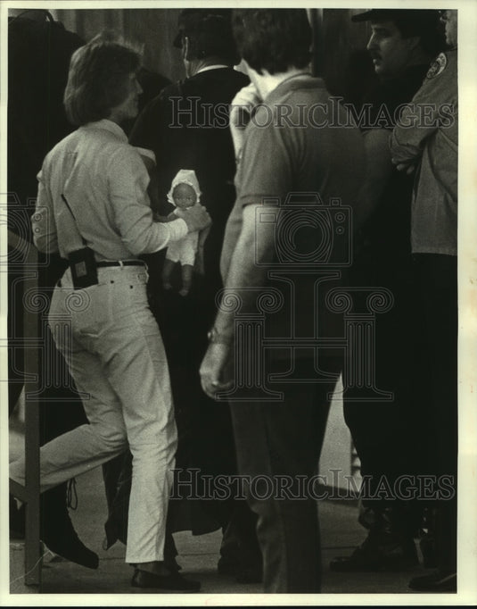 1986 Press Photo A NOPD officer carries Linda Hanchette's doll after surrender - Historic Images