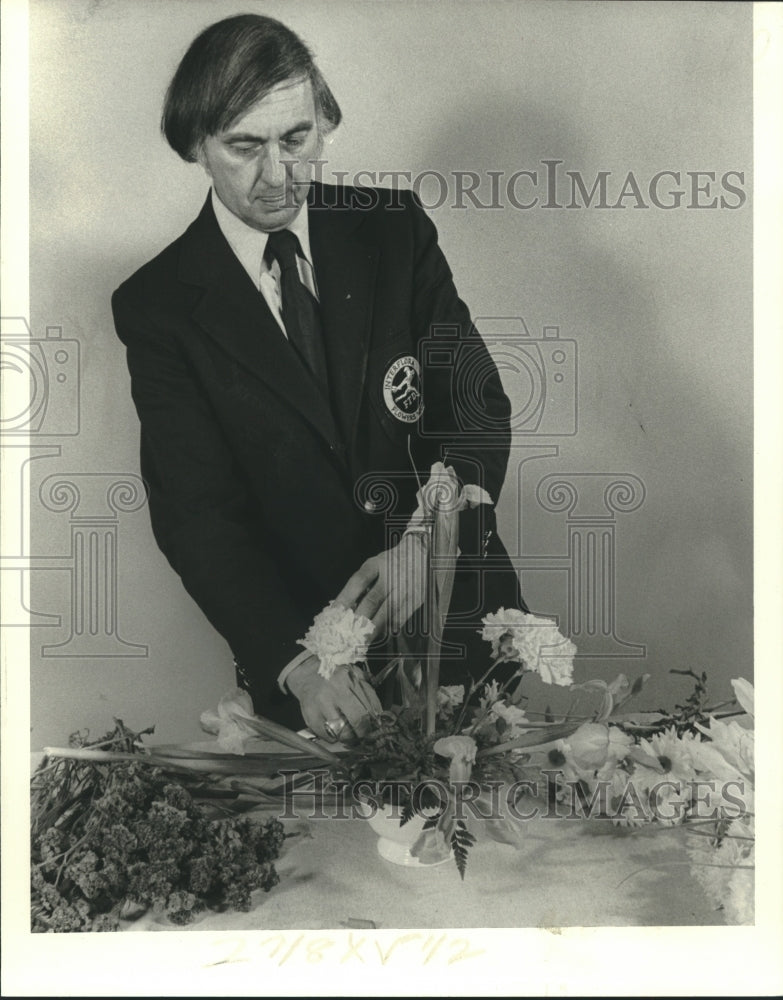 1979 Florist Claude Harwood Jr. on steps in flower arrangement - Historic Images