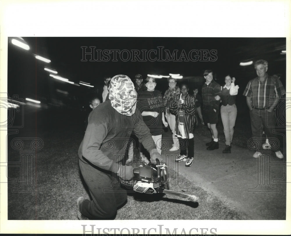 1995 Press Photo Person with chainsaw scares crowd outside haunted house - Historic Images