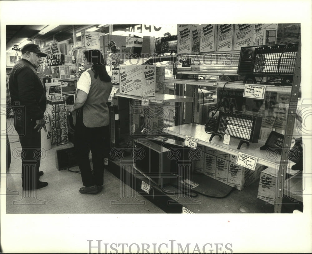 1987 Press Photo Sherran Cannon helps Harrold Miller with electric heaters - Historic Images