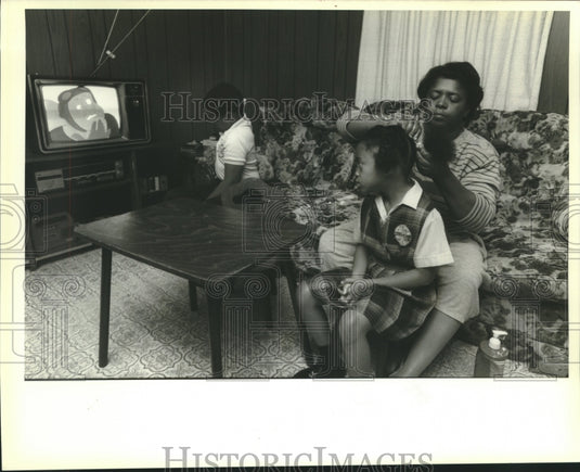 1989 Press Photo John watches TV while Betty Hebert fixes Erin's hair - Historic Images