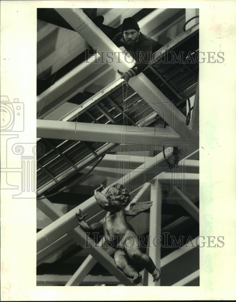 1986 Press Photo Romallis Brightman hangs angel from Hilton hotel lobby - Historic Images