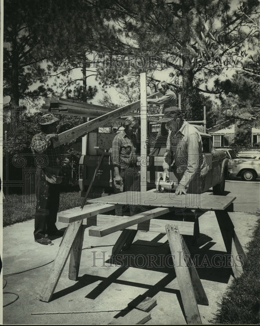 1973 Men line up and prepare lumber to be cut at a job site - Historic Images