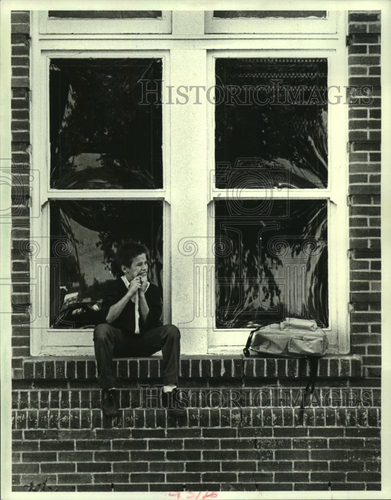 1987 Press Photo Stanley Grohoski sits on ledge of Holy Cross College building - Historic Images