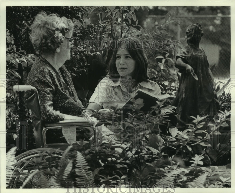 1975 Press Photo Carolyn McMahon reads to a patient on the grounds of hospital. - Historic Images