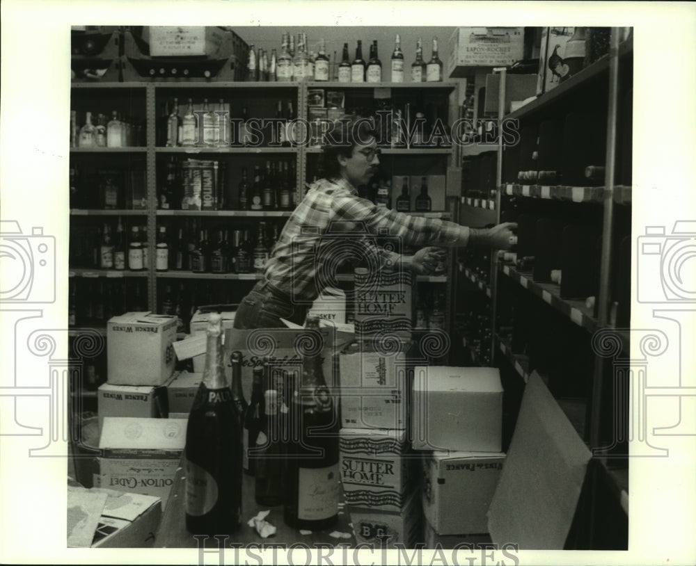 1986 Press Photo Philip Richardson, Wine and Liquor buyer is stacking shelves. - Historic Images