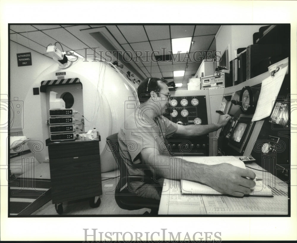 1994 Press Photo Technician John Wilson operates console of hyperbaric chamber. - Historic Images