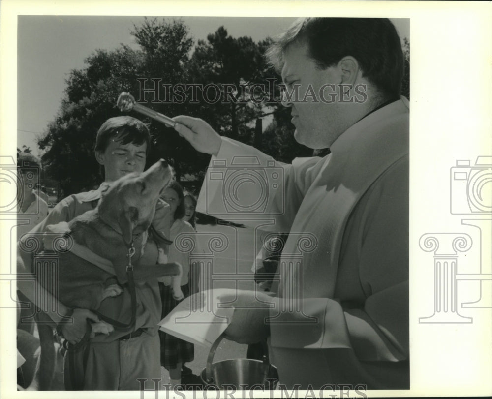 1989 Press Photo Rev. Ray Hymel blesses Donald McKoin&#39;s dog at St. Andrew School - Historic Images