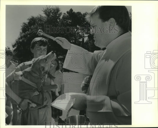1989 Press Photo Rev. Ray Hymel blesses Donald McKoin's dog at St. Andrew School - Historic Images