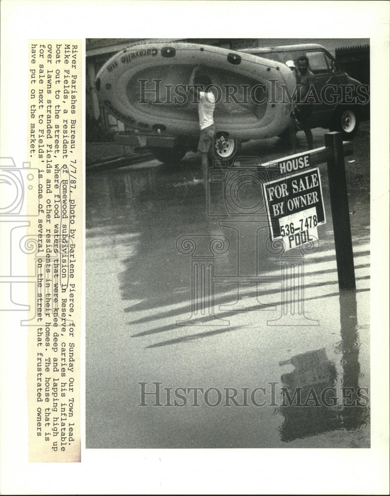 1987 Press Photo Mike Fields, carries inflatable boat to street due to flood - Historic Images