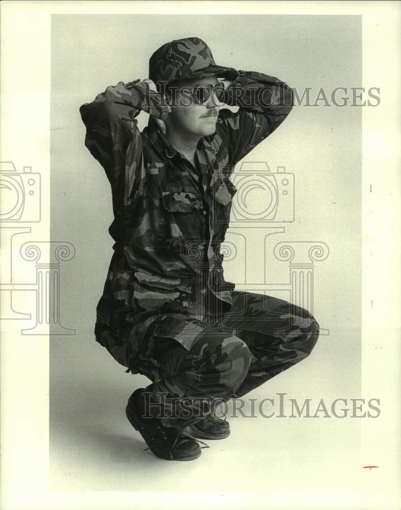 1985 A hunter in camouflage doing duck walk exercises - Historic Images