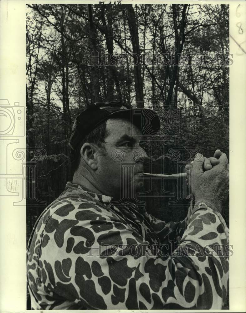 1982 Hunter wearing camouflage using a turkey call - Historic Images