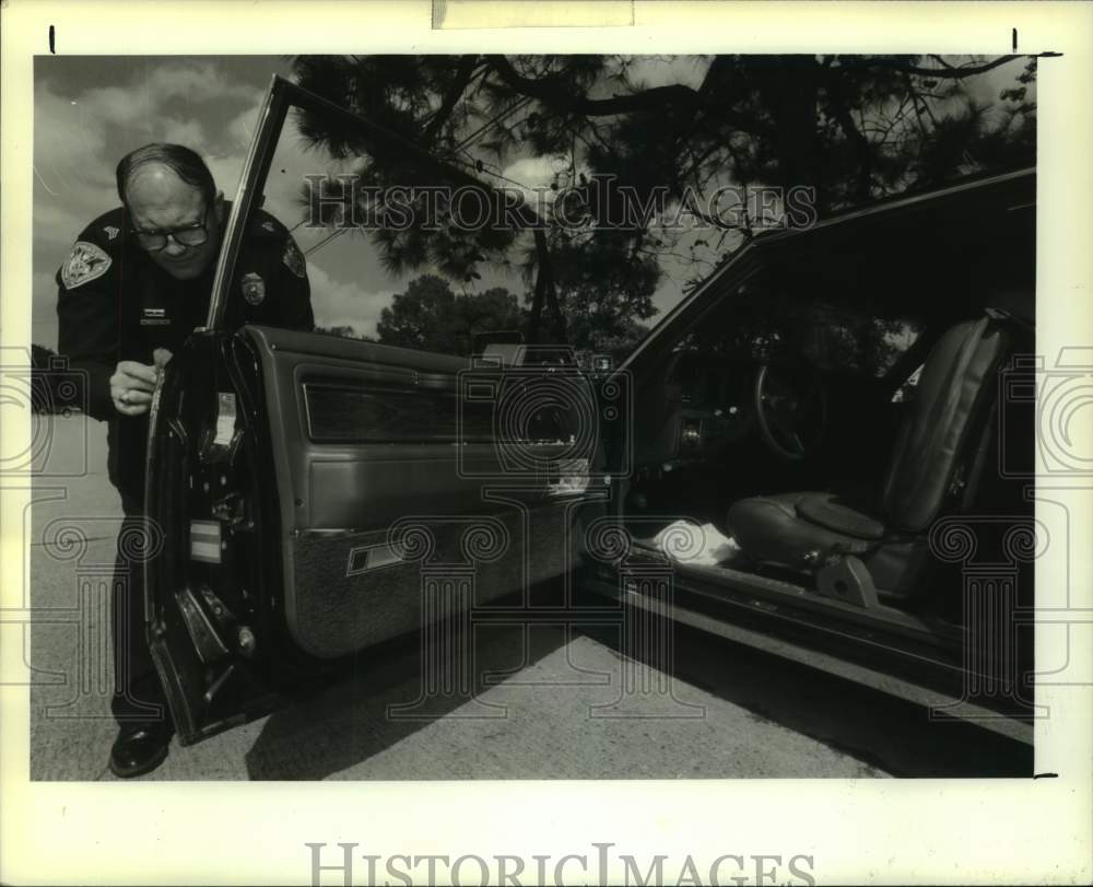 1990 Sergeant William Vieira examines the car of Billy Huntley - Historic Images