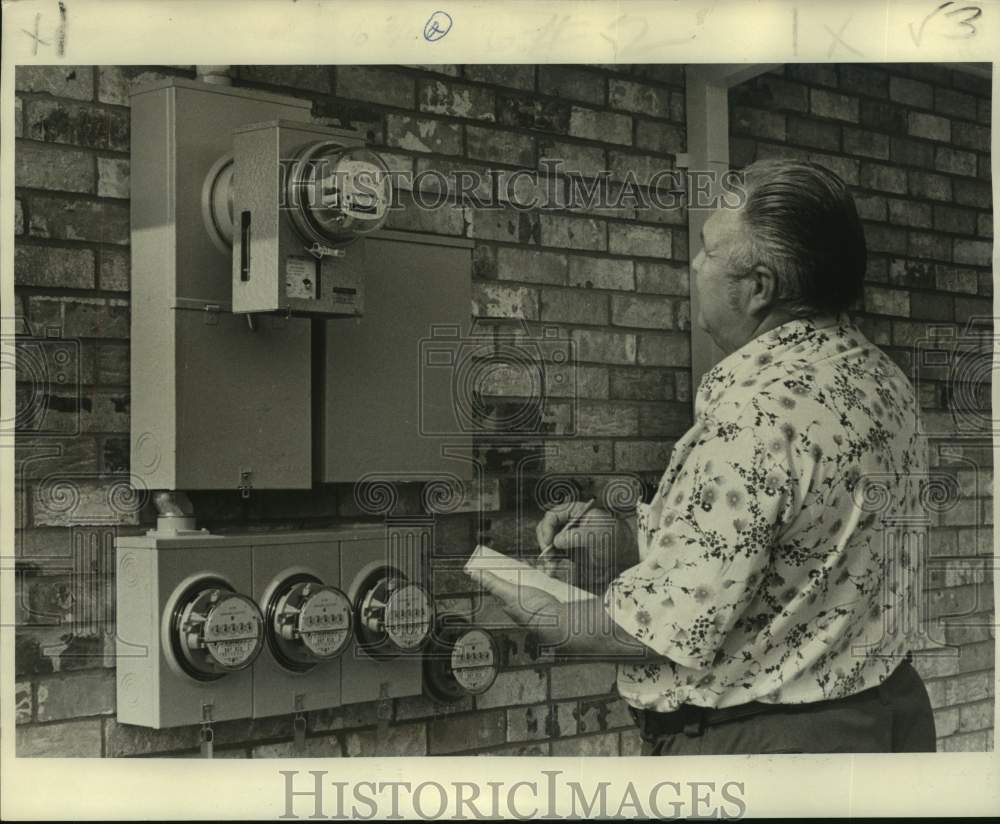 1976 Man checks meters of house - Historic Images