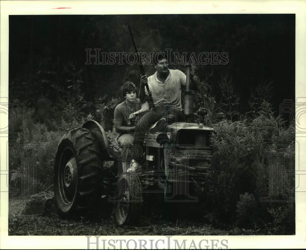 1986 Joe Cobla rides on the hood of tractor driven by Troy Lafrance - Historic Images