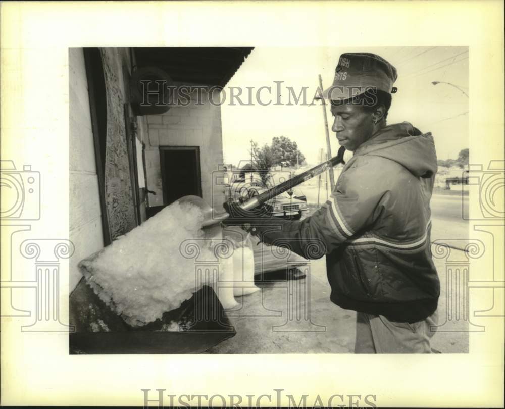 1989 Press Photo Quinston Calvin shovels crushed ice into a 45-pound bag. - Historic Images