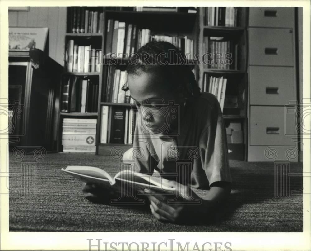 1989 Press Photo Literacy-Gilda Livious reads at home in front of the book case - Historic Images