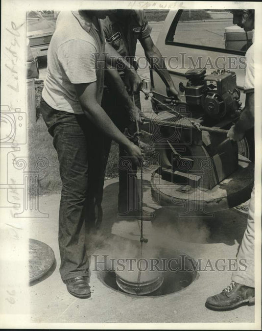 1976 Press Photo Smoke bomb lowered into manhole which will be covered - Historic Images