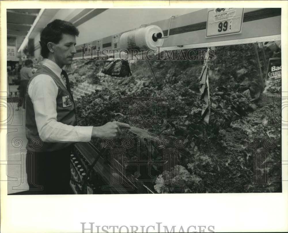 1990 Press Photo Employee spays produce at Winn-Dixie store in Bogalusa. - Historic Images