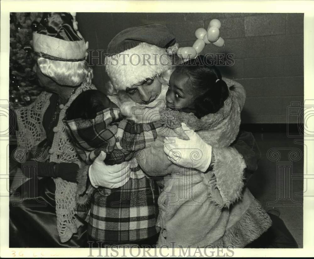 1986 Press Photo Letora &amp; Leshone Scott give Santa a big hug at Doll &amp; Toy Fund - Historic Images