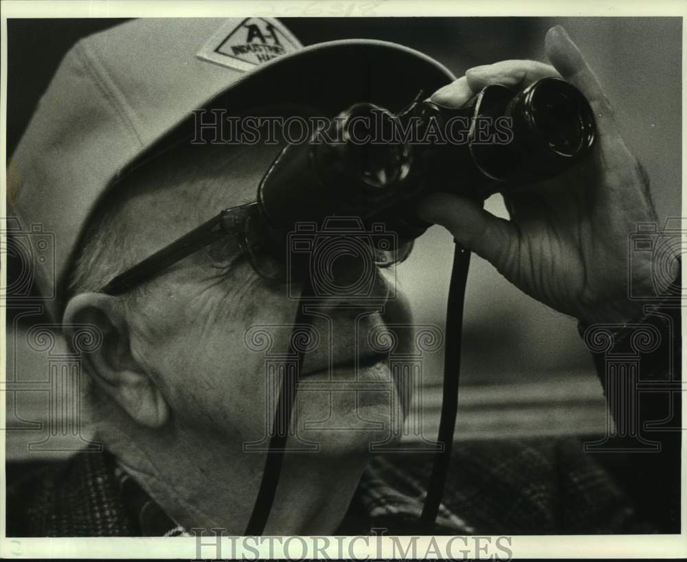 1987 Press Photo Fred Volles uses binoculars to watch race at Jefferson Downs - Historic Images