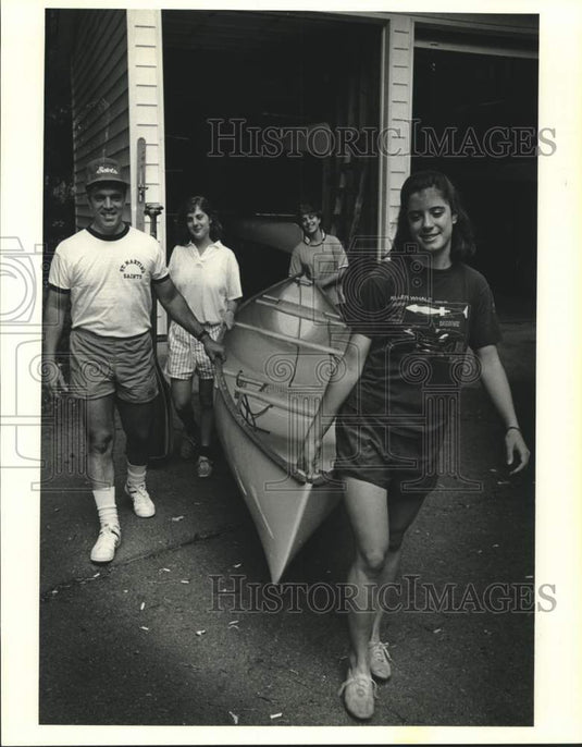 1986 Press Photo Regan Kelley and others shown carrying a boat - Historic Images
