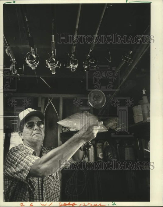 1987 Press Photo Willie Hof reaches for his favorite rod and reel for fishing - Historic Images
