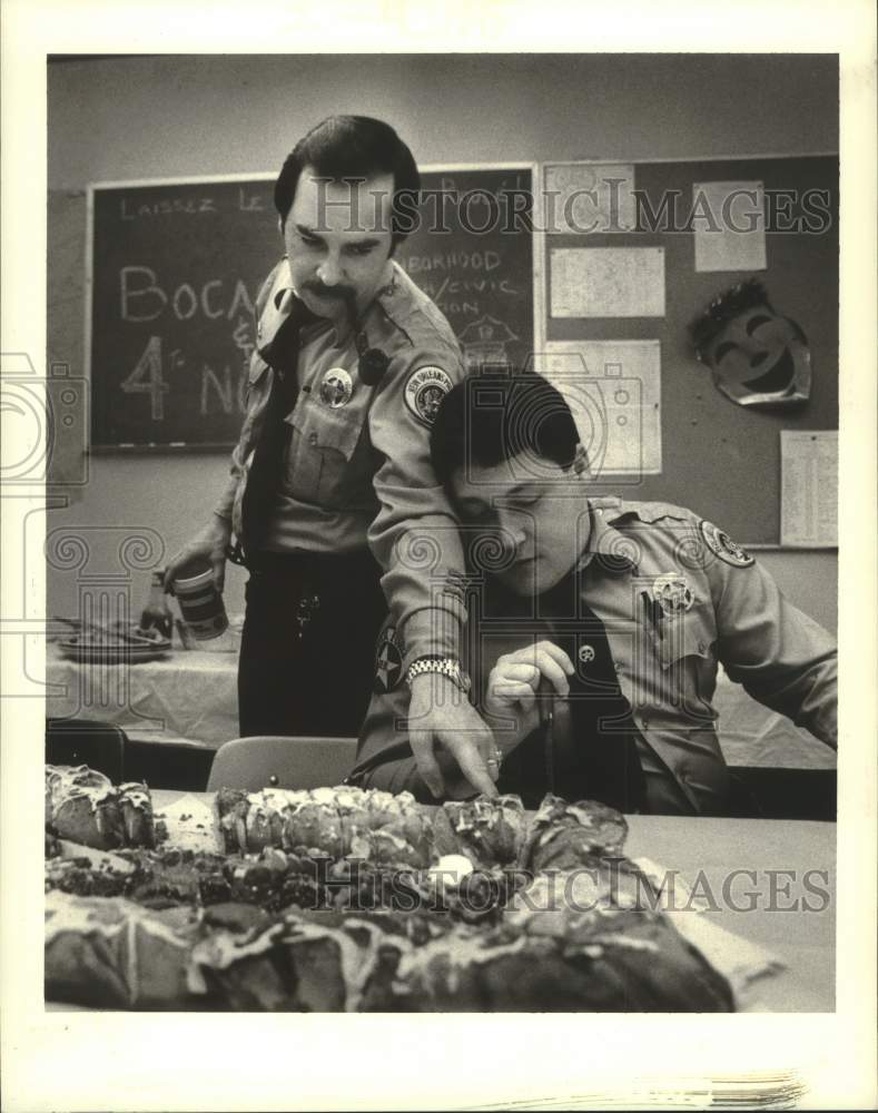 1987 Press Photo Police officers Don Bass and Robert Heindel examine a King Cake - Historic Images