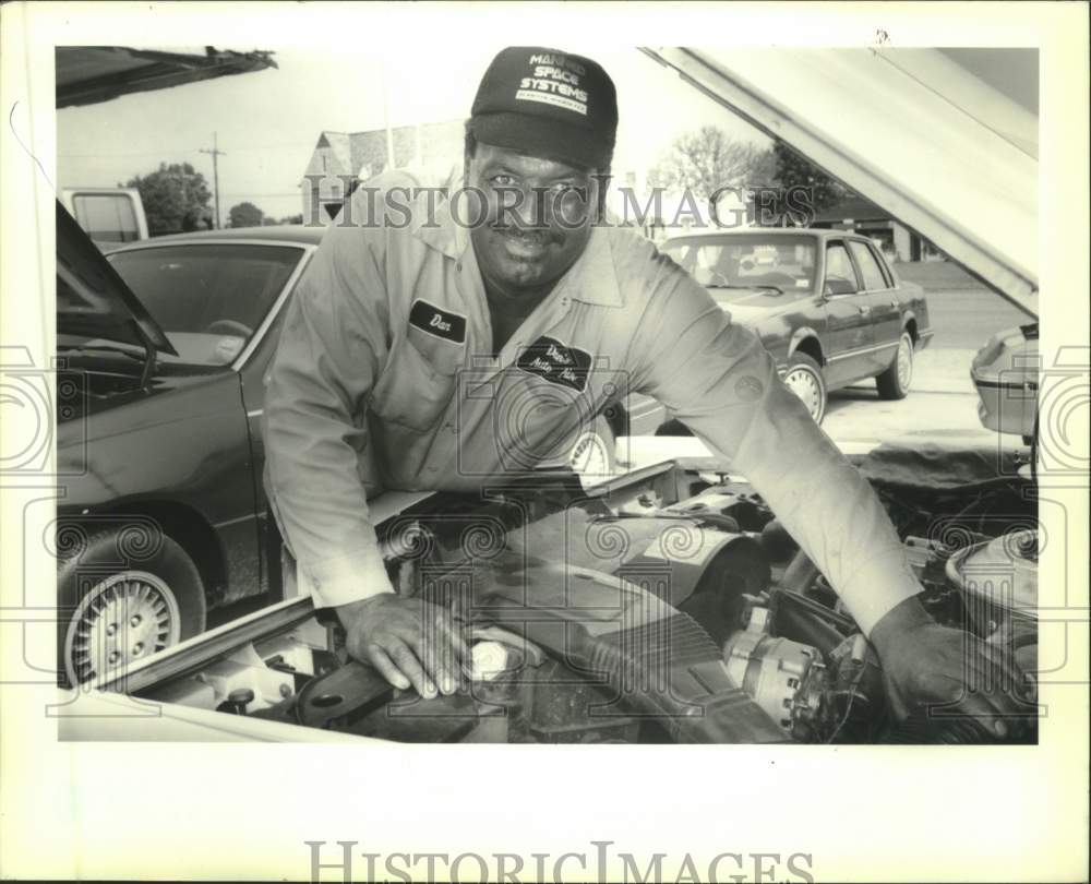 1991 Press Photo Dan Kirk talks about crime and jobs while repairing a car - Historic Images