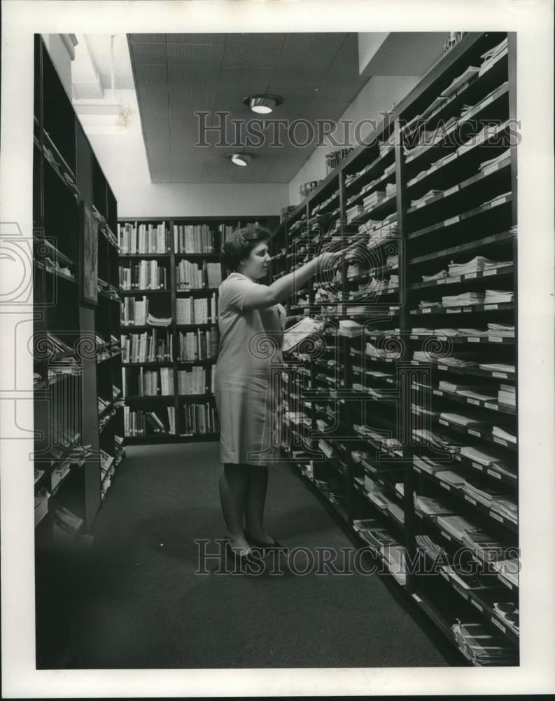 1968 Barbara Danna checks periodical collection at I-H Library - Historic Images