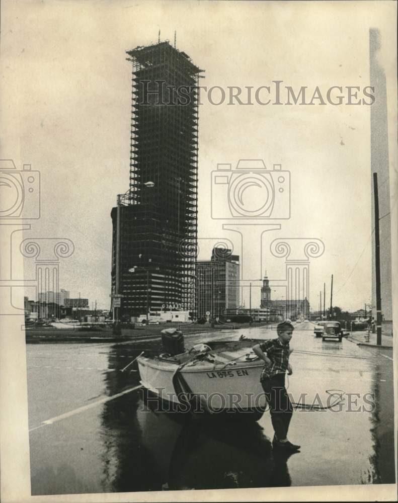 1965 Street view of flooded streets near Plaza Tower construction. - Historic Images