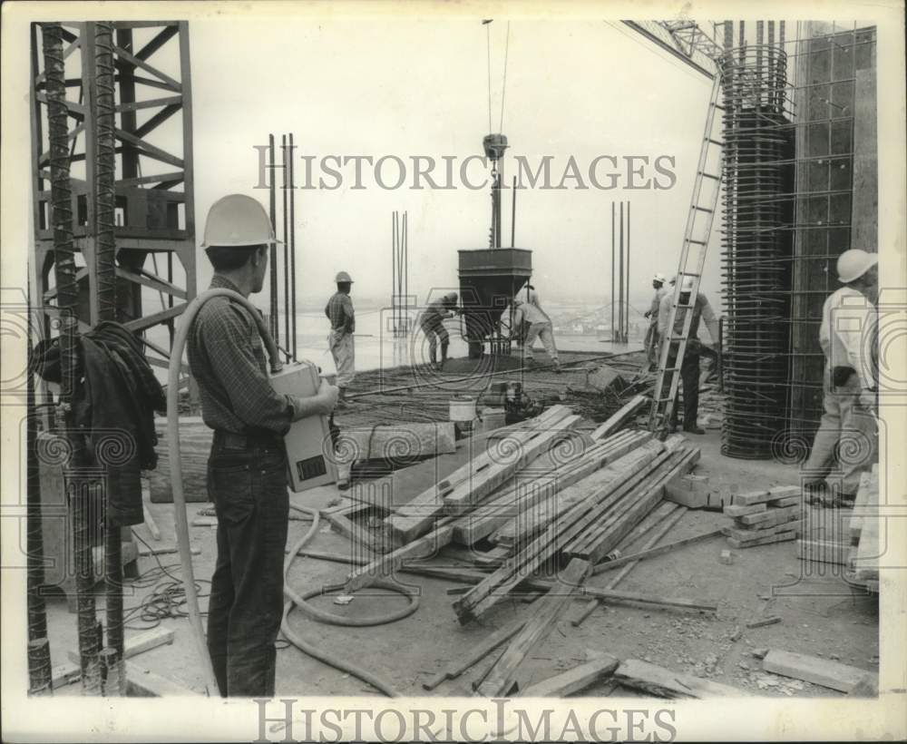 1965 Crane operator guides concrete bucket via remote control box-Historic Images