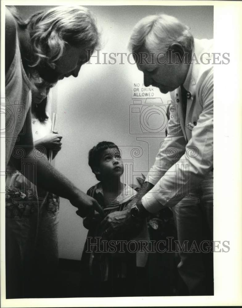 1994 Press Photo Doctor Herbert Marks adjusts Rhett LeBoeuf&#39;s hearing device - Historic Images