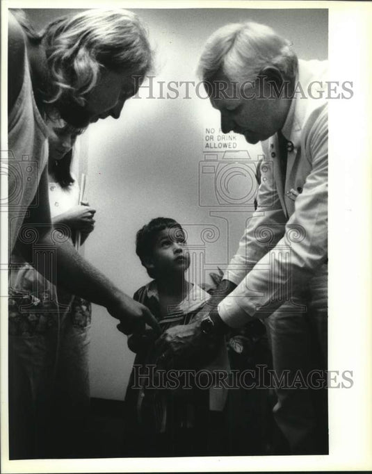 1994 Press Photo Doctor Herbert Marks adjusts Rhett LeBoeuf's hearing device - Historic Images