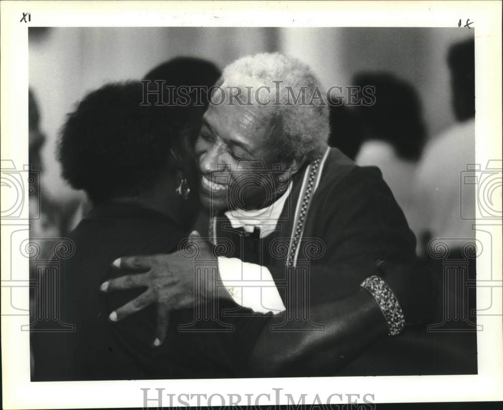 1991 Press Photo Father Jerome LeDoux hugs a parishioner at St. Augustine Church - Historic Images